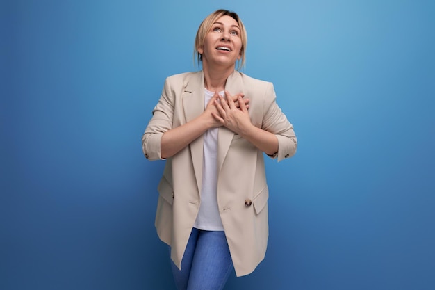 Primo piano di una giovane donna bionda gentile positiva in una giacca beige con emozioni sul viso