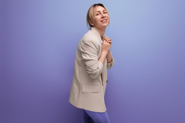 Closeup of a positive smiling blonde business woman in a jacket successful in work on the background