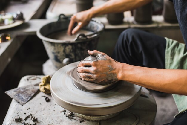 Closeup potter's hands shaping soft clay to make an earthen pot