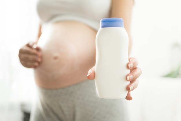 Closeup pregnant woman holding creme container