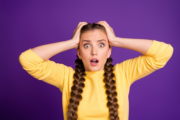 Closeup pretty lady long braids holding arms on head is over wear casual yellow jumper isolated purple color wall