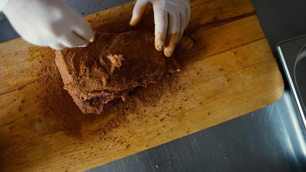 Closeup of professional chef man prepare meat with spice on cutting board at restaurant kitchen