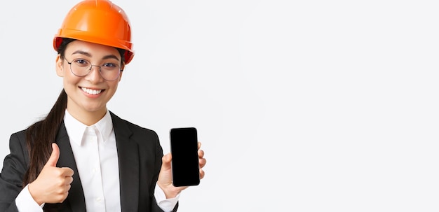 Closeup of professional smiling female engineer construction manager in business suit and safety hel