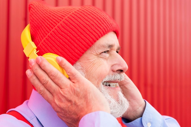 Closeup profile portrait of a happy retired hipster listening to music on headphones