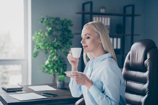 Ritratto di vista laterale del profilo del primo piano della ragazza vaga che beve caffè