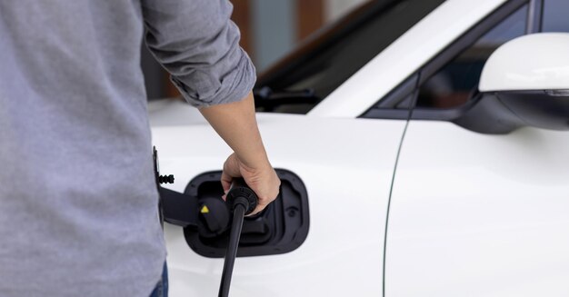 Closeup progressive asian man recharge his EV car at home charging station