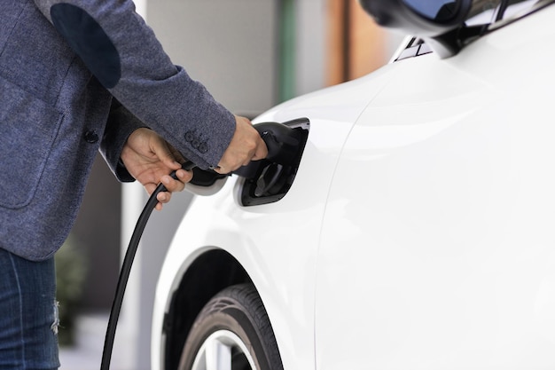 Closeup progressive asian man recharge his EV car at home charging station
