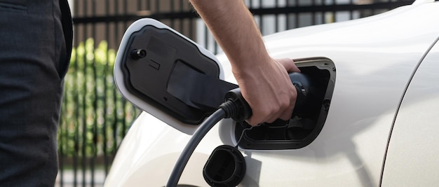 Photo closeup progressive businessman plugs charger plug from charging station to ev