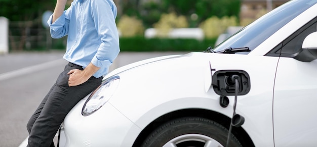 Closeup progressive businessman with electric vehicle at charging station