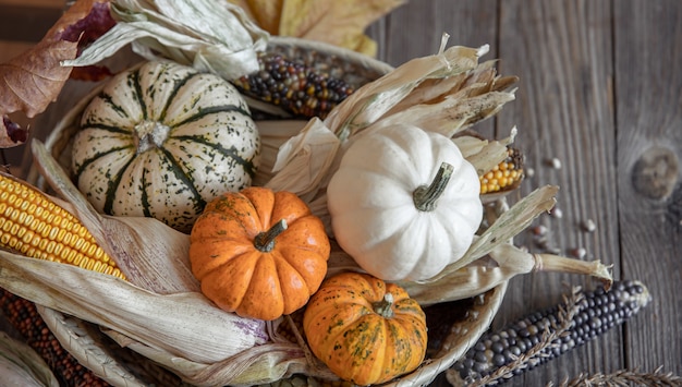 Closeup of pumpkin corn and autumn leaves on a wooden background