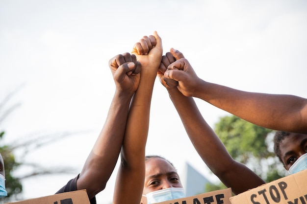 Closeup of the raised fists of a group of African guys protesting