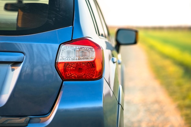 Closeup of rear red taillight and mirror of new clean blue SUV offroad car on rural road