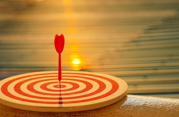 Closeup red dart arrow hitting in target center of dartboard Business goal or success goal marketing Strategy and business competition concept
