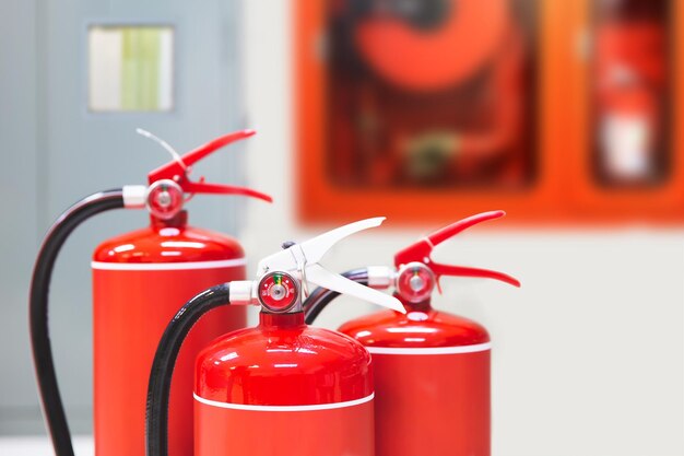 Photo closeup red fire extinguishers tank in the building