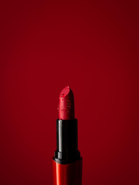 Photo closeup on red lipstick in splashes of water on a red background