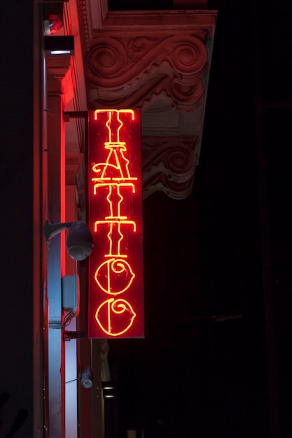 Closeup on a red neon light shaped into the word Tattoo