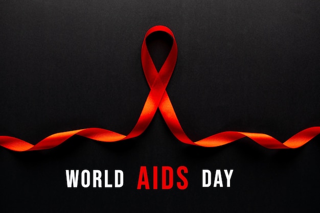 Foto consapevolezza del nastro rosso del primo piano su carta nera per la campagna della giornata mondiale contro l'aids.