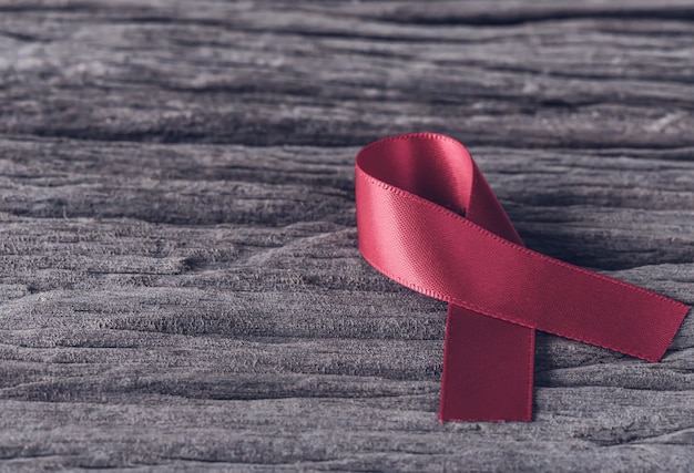 Closeup red ribbon awareness on wooden background for World Aids day campaign.