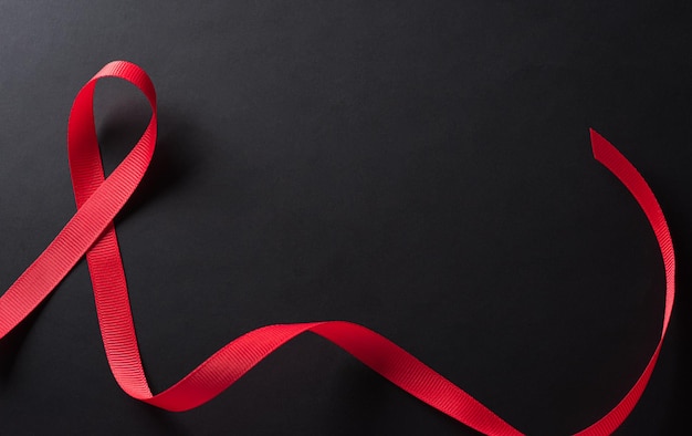 Photo closeup red ribbon hiv world aids day awareness ribbon on black background healthcare and medicine concept