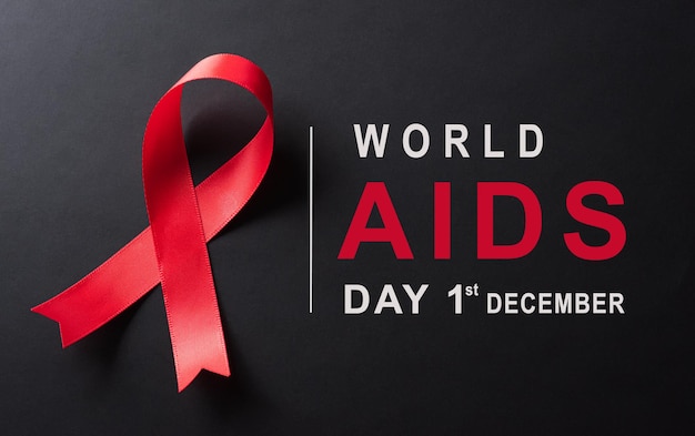 Closeup red ribbon HIV world AIDS day awareness ribbon on black background Healthcare and medicine concept