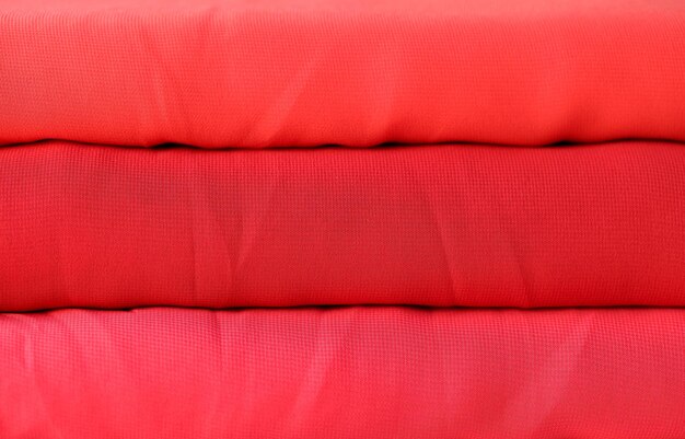 Closeup of red rolls of knitted fabric texture background cloth with different color shades of