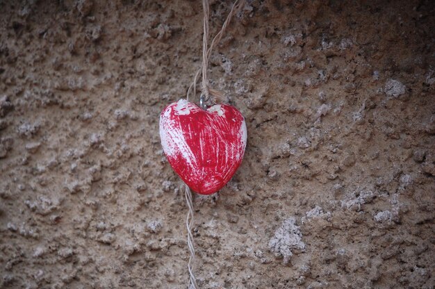 Photo closeup of red wooden heart in a wall background