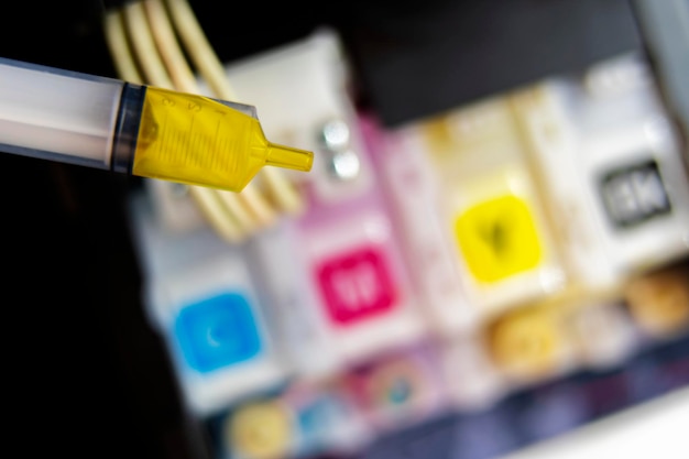 Closeup refilling ink into a yellow ink tank printer at office\
the printer ink is available in blue red yellow black cmyk