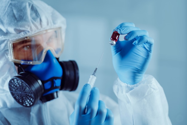 Closeup researcher holds a syringe and an ampoule with the tested vaccine