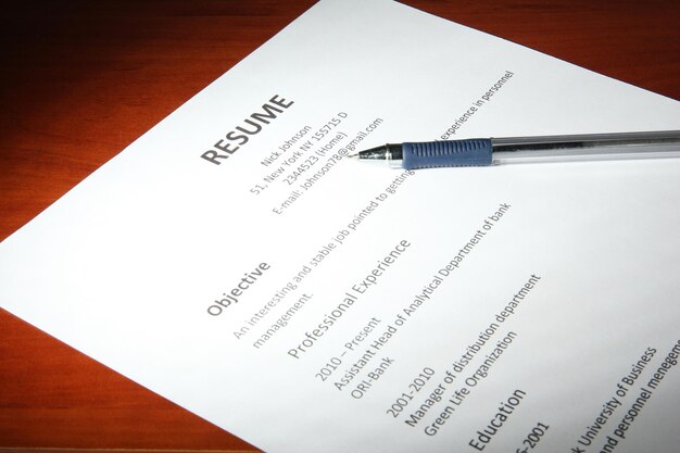 Photo closeup of resume with pen on wooden table