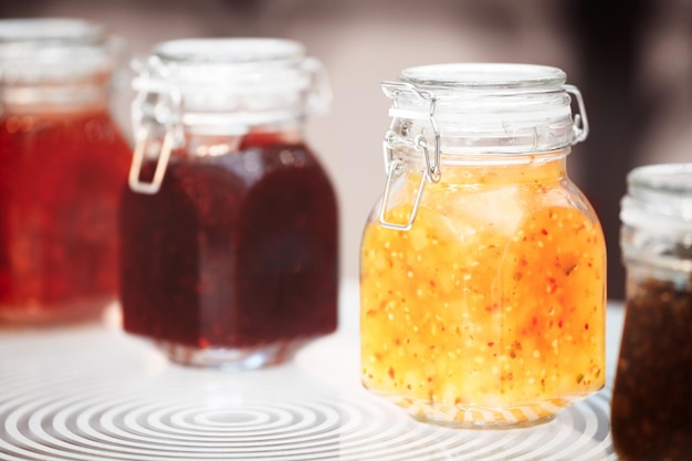 Closeup rij van verschillende glazen met rood geel oranje potten jam conserve confiture pozzy op tafel ontbijt concept keuken achtergrond gezond eten concept instandhouding concept