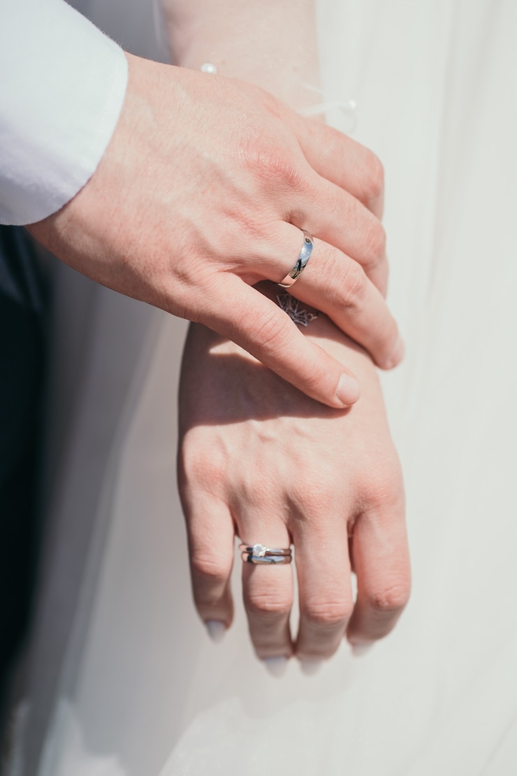 Photo リングのクローズアップ新婚新郎は優しく花嫁の手に触れます夫と妻は手をつないでいます...