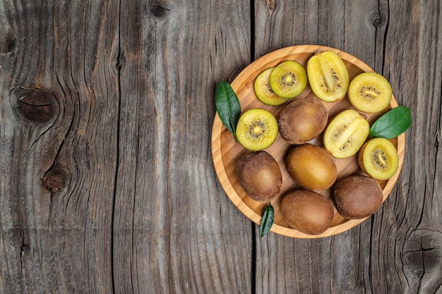 木製の背景にクローズ アップ熟したゴールデン キウイ フルーツ テキスト トップ ビューの健康的な果物のコンセプトの場所