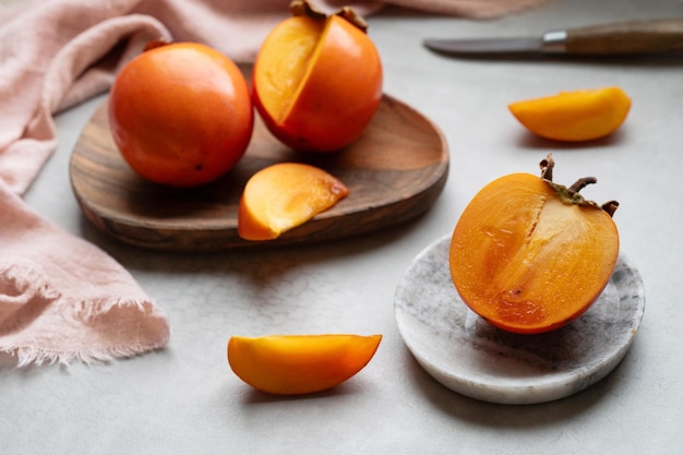 Closeup of ripe Sharon persimmon and slices on plates