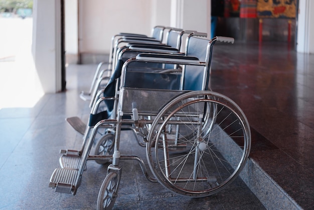 Primo piano fila di sedie a rotelle vuote che parcheggiano all'aperto preparate per le persone anziane e i passeggeri disabili