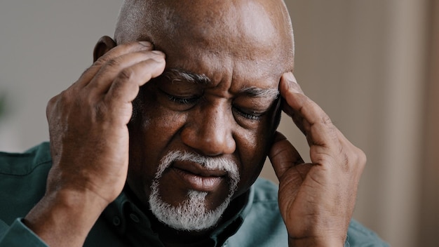 Closeup sad suffering elderly african american old sick ill man feeling headache chronic migraine