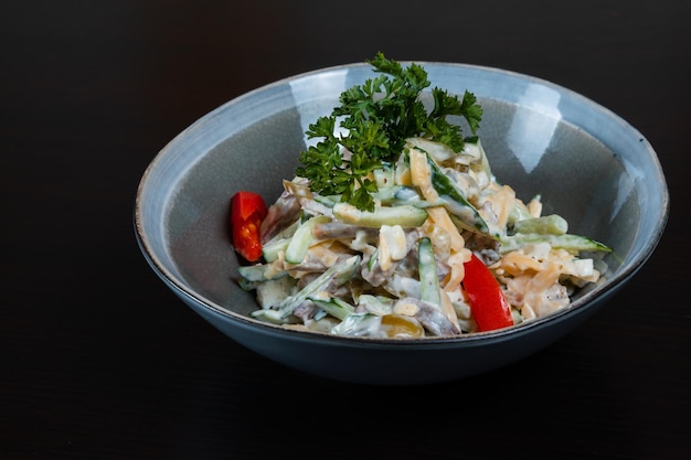 Closeup of salad with meat vegetables and mayo on a black background