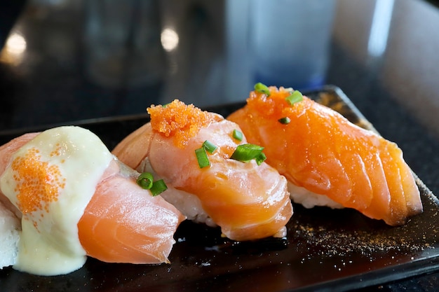 Photo closeup salmon sushi in black plate.