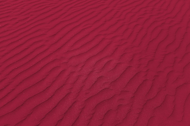 Closeup of sand pattern of a beach. New 2023 trending PANTONE 18-1750 Viva Magenta colour