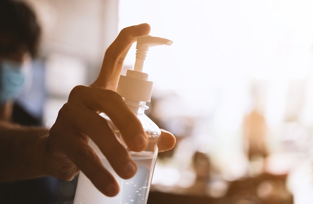 Closeup sanitizer with 75% concentrated alcohol in men's hands with soft-focus and over light in the wall