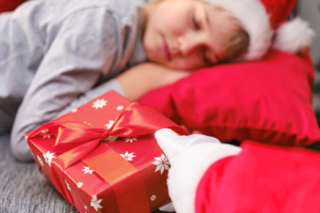 Foto primo piano la mano di babbo natale fa un regalo di natale a un bambino addormentato