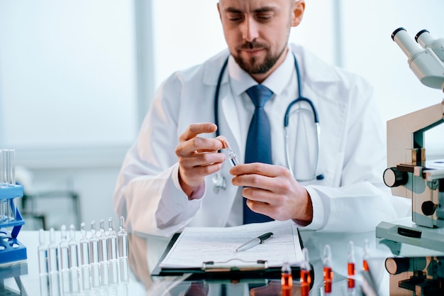 Closeup  scientist looking at an ampoule with a vaccine 