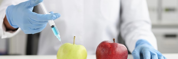 Closeup of scientist in white coat making injection into green\
apple in laboratory vegetables