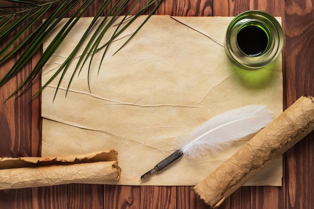 Closeup of scroll and quill near inkpot on wooden table