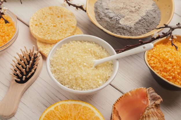 Closeup of sea salt with orange essential oil and face cream on white background. Skincare and spa concept