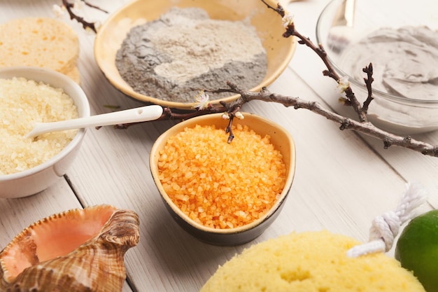 Closeup of sea salt with orange essential oil and face cream on white background. Skincare and spa concept