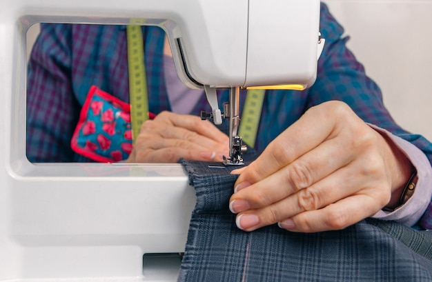 Closeup of seamstress hands working with clothing item on a sewing machine