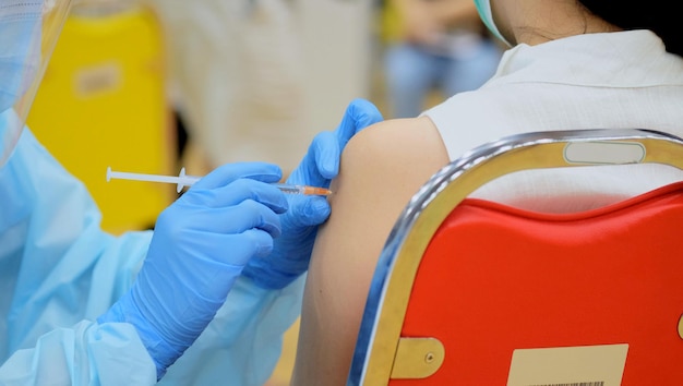 Closeup and selective focus of doctor hands who is vaccinating on upper arm of young woman