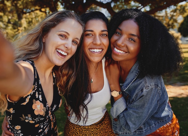 closeup self portrait of smiling young multiethnic female friends taking selfie in the park women taking a selfie in the park on a bright day