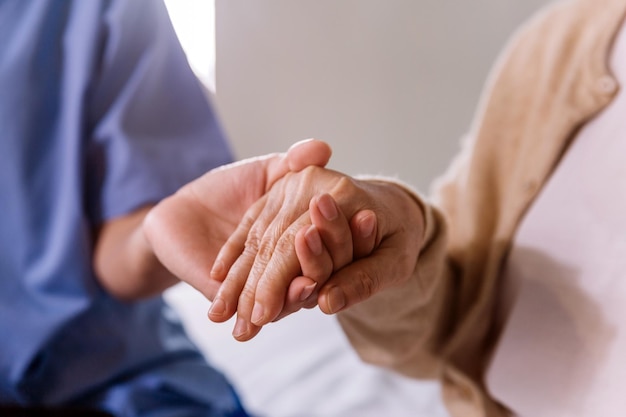 Closeup senior Asian woman hand with her caregiver helping hands Caregiver visit at home