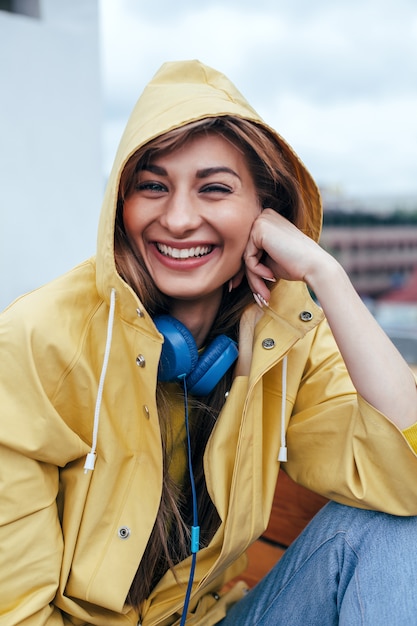 Closeup sensual portrait of young smiling happy woman posing with blue earphones outdoor